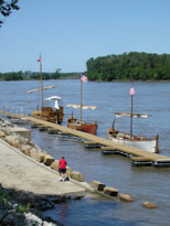 Photo: Lewis and Clark’s entire flotilla is visible here.  It is easy to see why the expedition distinguished between the smaller vessels (called pirogues) by their hull color (white and red).  The largest of the three vessels (today it is commonly referred to as a “keelboat” but Lewis and Clark called it “the barge”) is furthest from the camera.