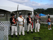 Photo: Interpreters dressed as Jeffersonian soldiers present arms as they salute the playing of the National Anthem.