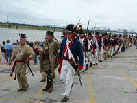 Photo:  Reenactors commemorate the arrival of the Lewis and Clark Expedition in St. Louis in ceremonies on the west bank of the Mississippi. The “civilian” (in the center) portrays George Drouillard. 