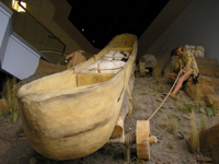 Photo: Close up of the rear of the same canoe which also shows a portion of the hand made wheeled carriage.  The expedition did not haul all of their canoes over the eighteen mile route; instead they carried an experimental iron framed boat with them to the “Lower Portage Camp” which they planned to use in lieu of additional canoes for their journey further westward.  The Red and White Pirogues had already cached above the falls to await the expedition’s eventual return.