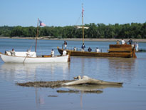 Photo: The white pirogue sails past the reproduction keelboat into the inlet marking the mouth of the Bad River.  Lewis and Clark’s expedition consisted of three vessels, the keelboat and two pirogues.  However, the arrival of the red pirogue was slightly delayed due to unexpected difficulties.