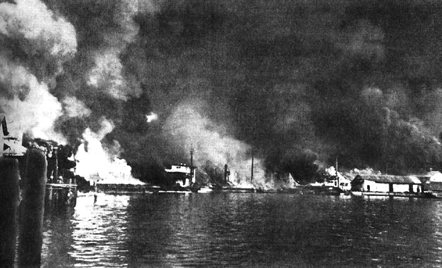 Photo:  At Cavite Navy Yard, small-arms shells explode (left) as the torpedo-loaded barge (center) burns
