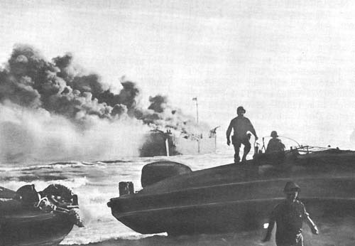 Photo:  Landing at Gela.  An LST loaded with ammunition burns offshore after a hit from a dive bomber