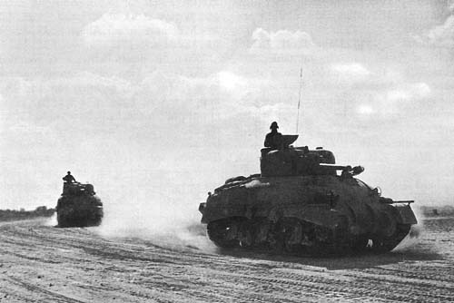 Photo:  Two Sherman M4 tanks moving toward the front.