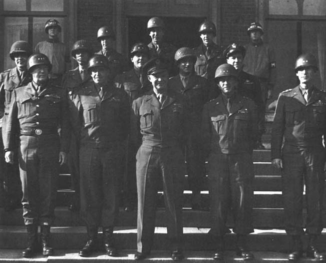 Photo: Thirteen Commanders of the Western Front photographed in Belgium, 10 October 1944. Front row, left to right: General Patton, General Bradley, General Eisenhower, General Hodges, Lt. Gen. William H. Simpson. Second row: Maj. Gen. William B. Kean, Maj. Gen. Charles E. Corlett, Maj. Gen. J. Lawton Collins, Maj. Gen. Leonard P. Gerow, Maj. Gen. Elwood R. Quesada. Third row: Maj. Gen. Leven C. Allen, Brig. Gen. Charles C. Hart, Brig. Gen. Truman C. Thorson. 