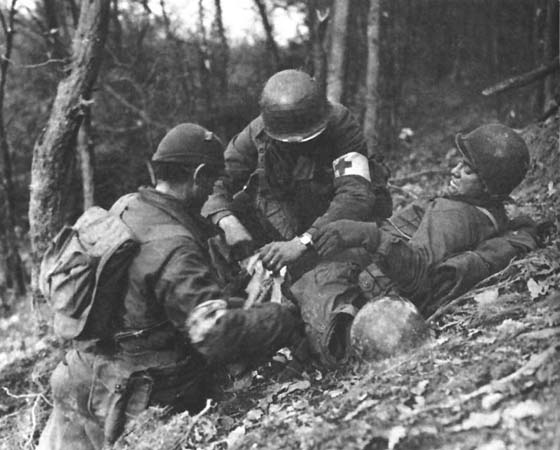 Photo: Medics aid a wounded soldier in the woods.