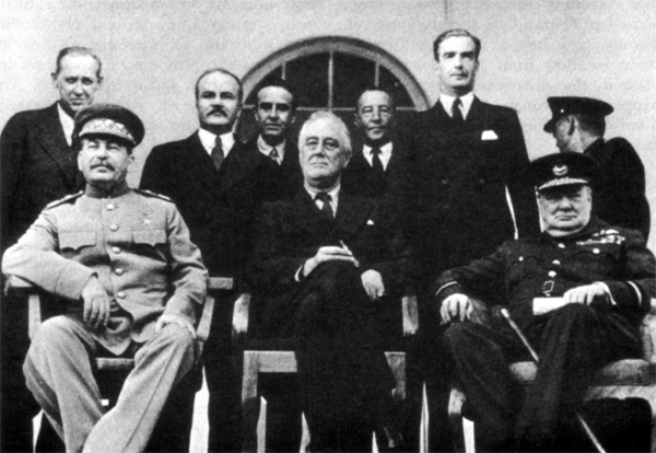 THE BIG THREE IN PORTICO OF THE SOVIET LEGATION, TEHRAN. Seated on left is Marshal Joseph Stalin. Standing from left: Harry Hopkins, Vyacheslav M. Molotov, W. Averell Harriman, Sir Archibald Clark Kerr, and Anthony Eden. 