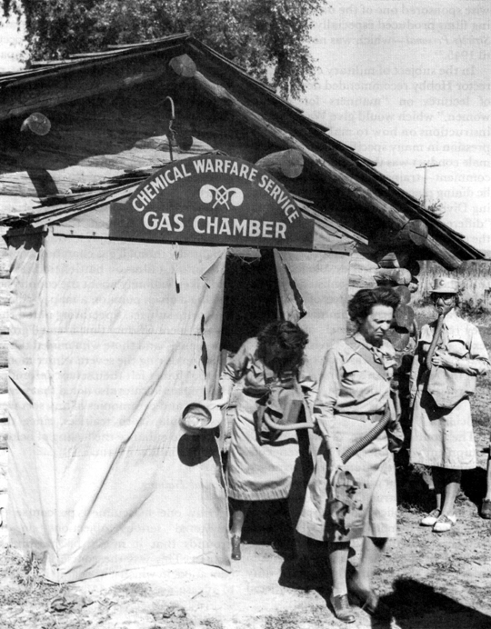 CHEMICAL WARFARE TRAINING. Women remove their gas masks before leaving the chamber, as ordered, thus experiencing the effects of tear gas.
