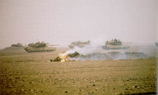 1st Armored Division Elements Passing the Burning Remnants of an Iraqi Tank