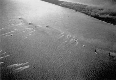 Landing craft pass supporting warships during the invasion of Eniwetok.