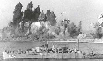 The USS Begor lies off the port of Hungnam as demolition charges destroy the 
  dock facilities on 24 December 1950.