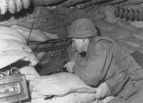 Photo: A soldier from the 180th Infantry mans a machine gun from inside a bunker